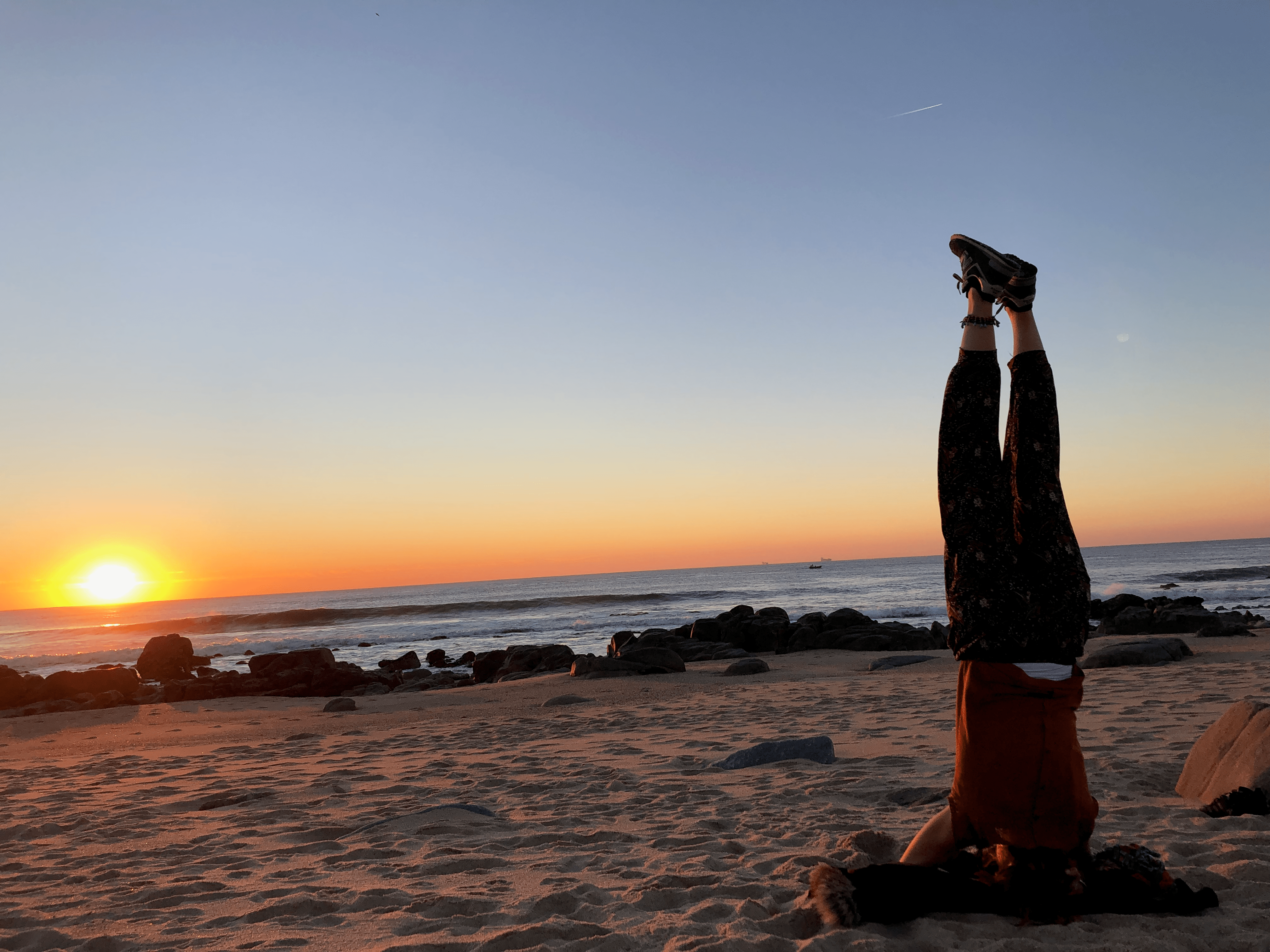 Personne faisant la position du poirier au coucher du soleil, symbolisant le lâcher-prise, la connexion corps-esprit et le retour à soi. Sophrologue Nice, inspirant le bien-être.