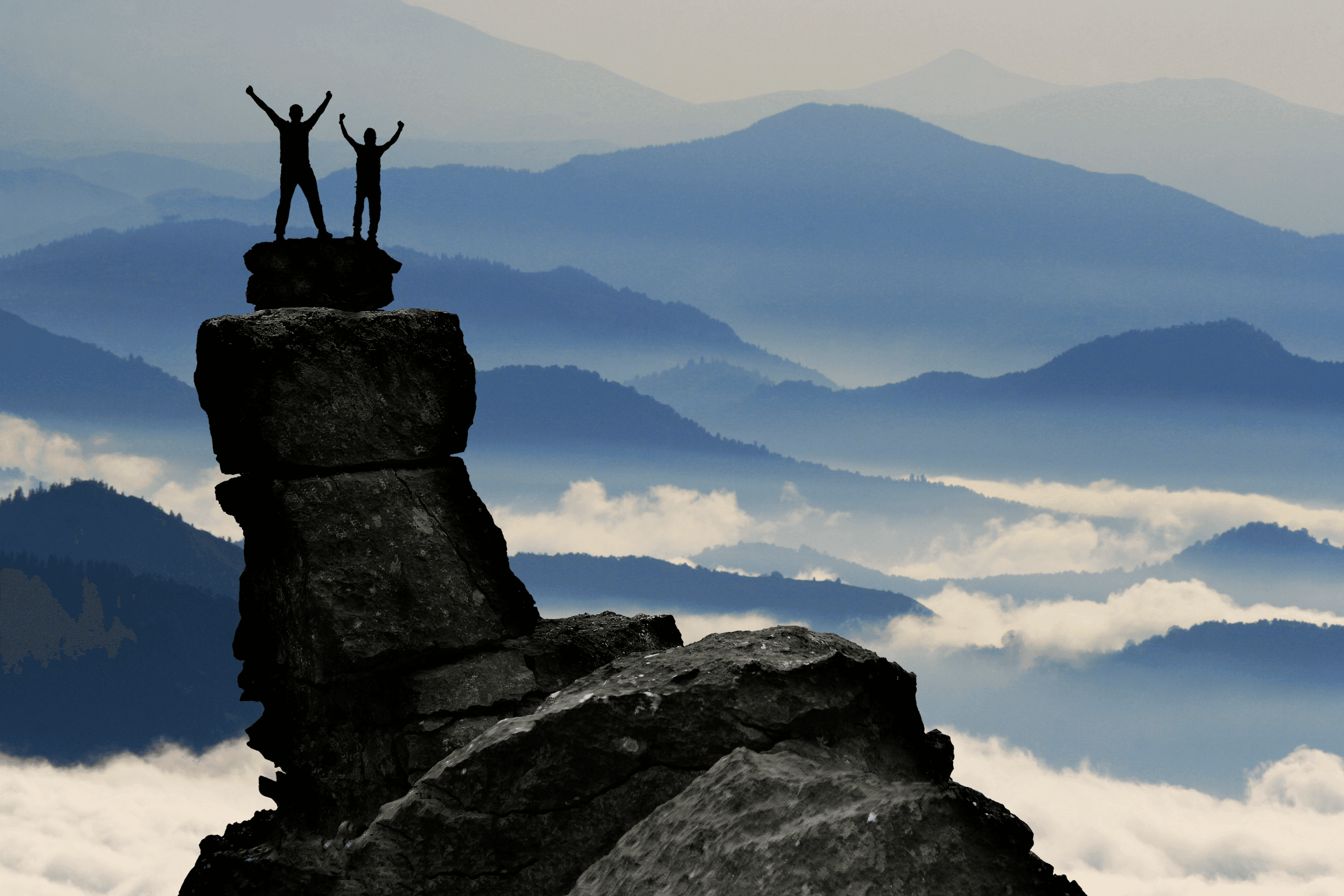 Deux personnes en haut d'une montagne célébrant leur accomplissement, symbolisant la confiance en soi, l'achèvement d'un objectif et la connexion avec la nature.