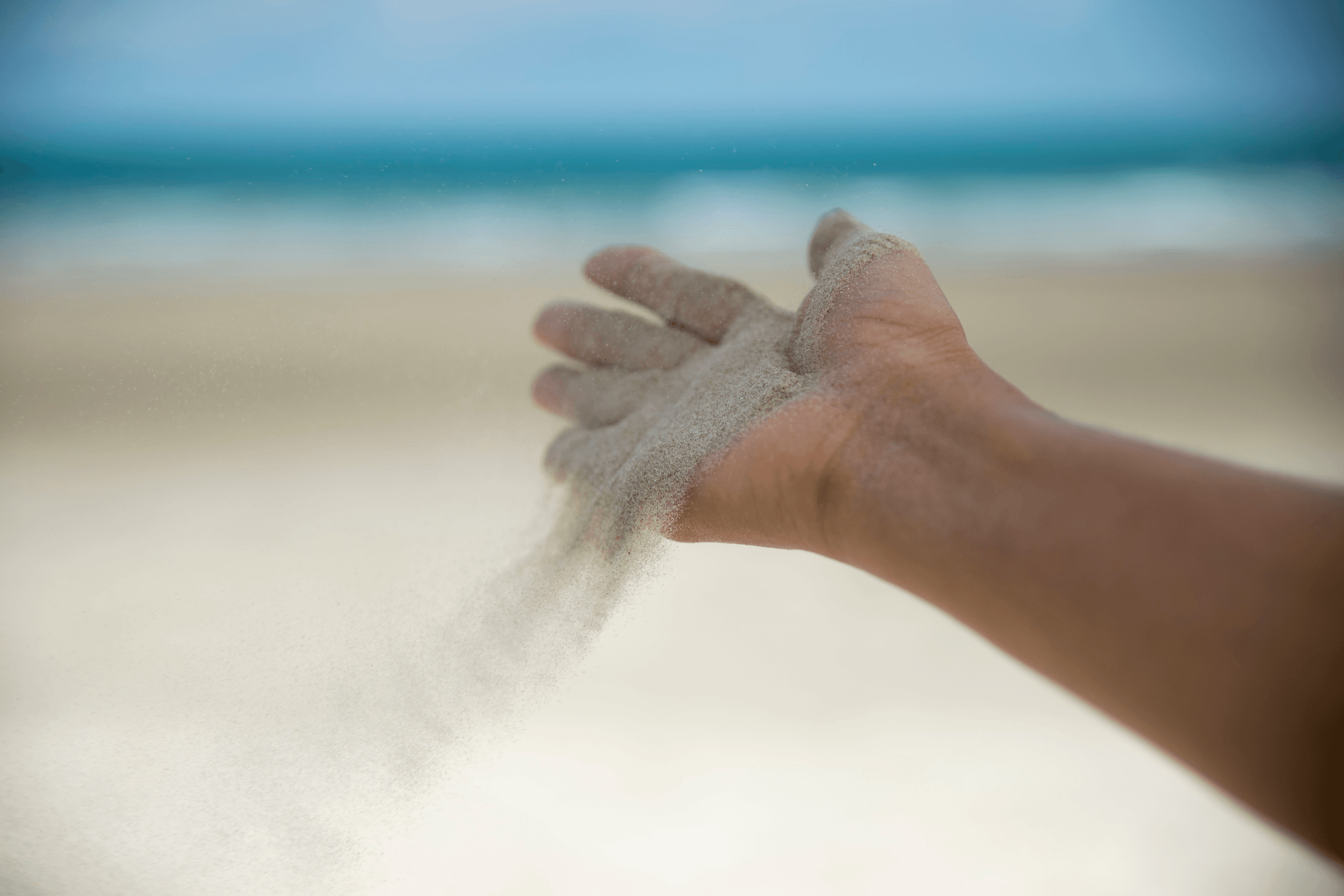 Main laissant le sable s'écouler, symbolisant le lâcher-prise, l'apaisement et l'équilibre dans la vie, qui peuvent être obtenus grâce à la sophrologie ou la respiration.